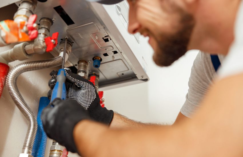 Closeup of plumber using screwdriver while installing new steel hot water central heating system in apartment. Manual work, maintenance, repair service concept