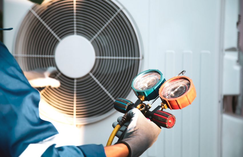 Mechanic air conditioner technician using manifold gauge checking refrigerant for filling home air conditioning and air duct cleaning and maintenance outdoor compressor unit.